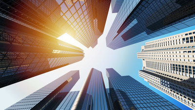 view from street level of sun peeking through skyscrapers